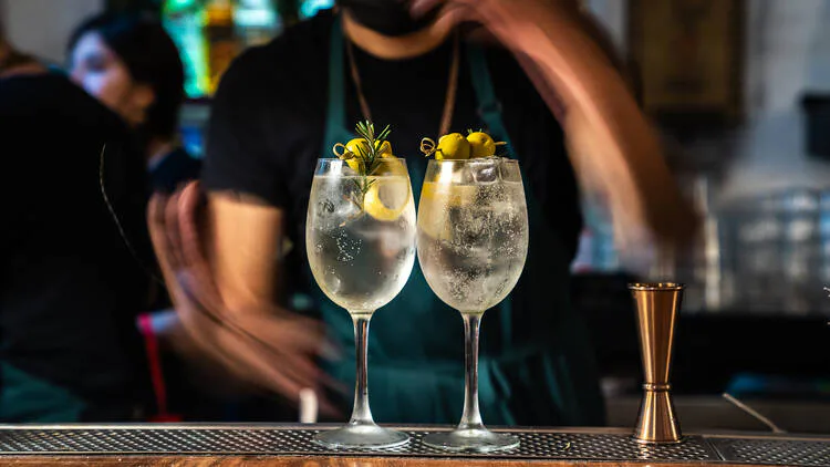 Servicio de cocteles en dos copas altas sobre la barra.
