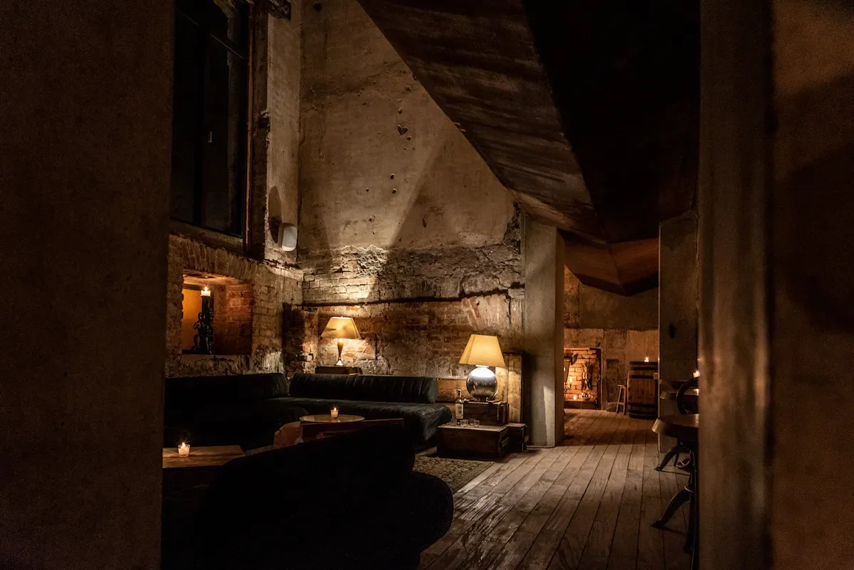 Salón de Taverna visto en profundidad, con madera, muros históricos y luz tenue.