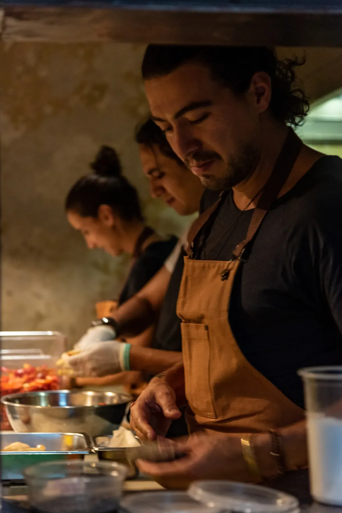 Equipo de cocina trabajando entre vapor y luz cálida.